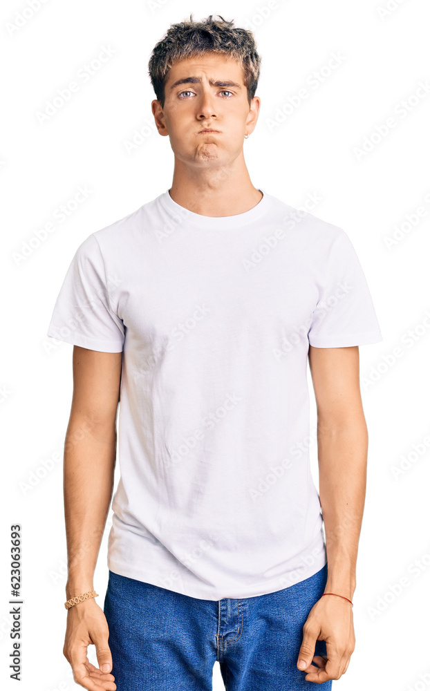 Young handsome man wearing casual white tshirt puffing cheeks with funny face. mouth inflated with air, crazy expression. Young handsome man wearing casual white tshirt puffing cheeks with funny face. mouth inflated with air, crazy expression.