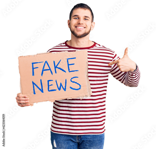 Young handsome man holding fake news message banner pointing finger to one self smiling happy and proud