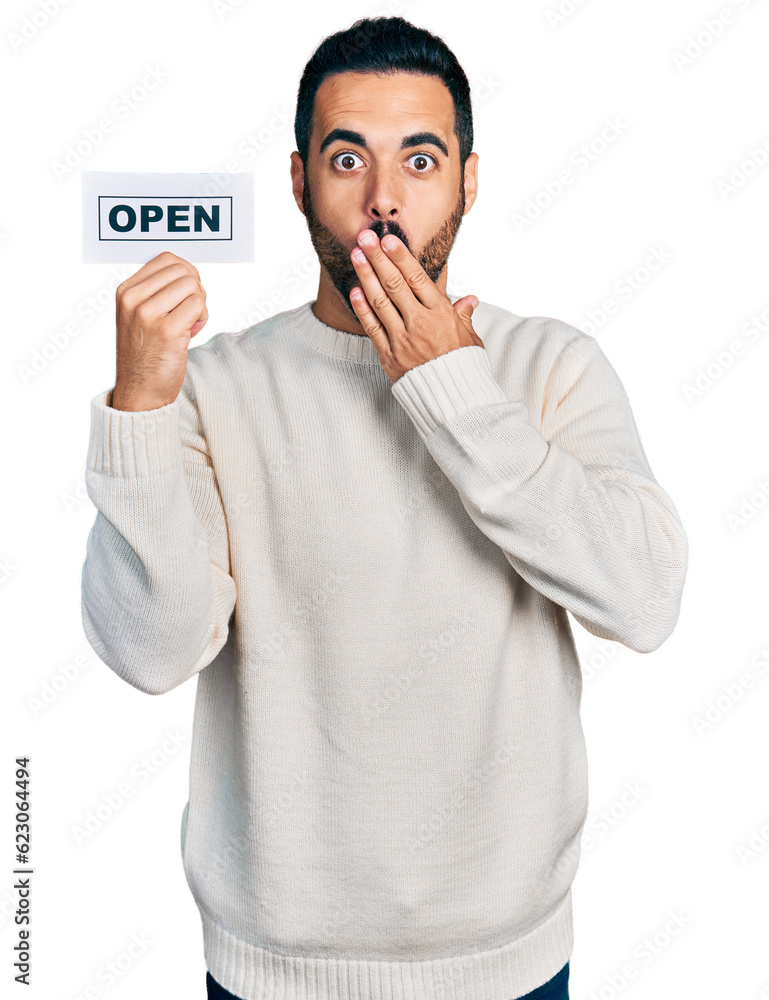 Young hispanic man with beard holding open banner covering mouth with hand, shocked and afraid for mistake. surprised expression Young hispanic man with beard holding open banner covering mouth with hand, shocked and afraid for mistake. surprised expression