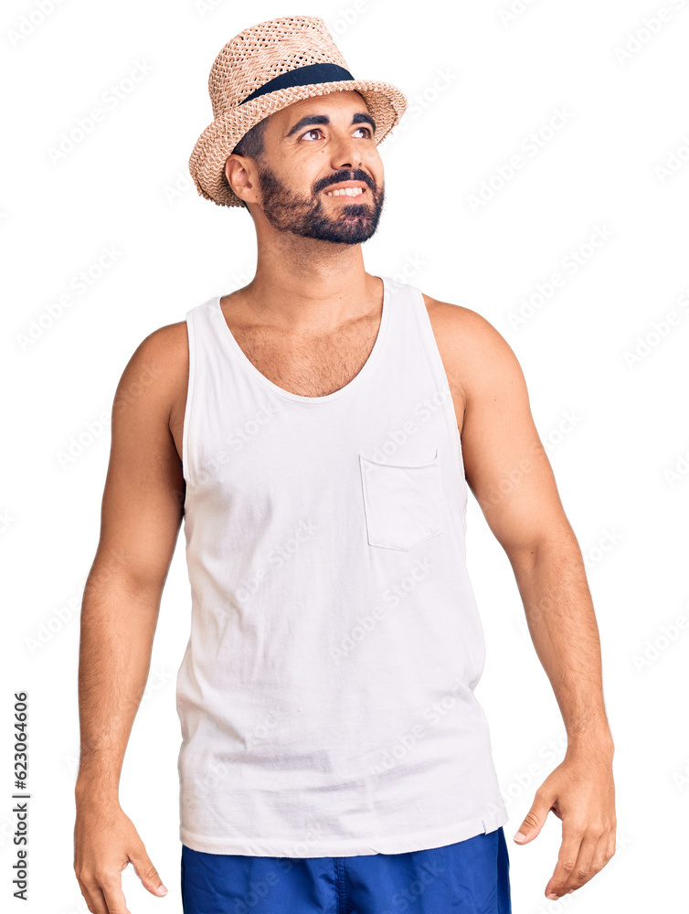 Young hispanic man wearing casual summer hat looking away to side with smile on face, natural expression. laughing confident. Young hispanic man wearing casual summer hat looking away to side with smile on face, natural expression. laughing confident.