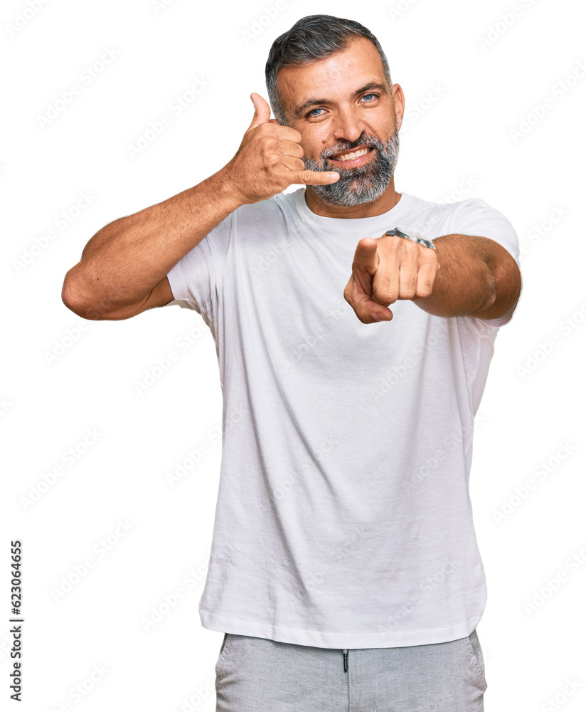 Middle age handsome man wearing casual white tshirt smiling doing talking on the telephone gesture and pointing to you. call me. Middle age handsome man wearing casual white tshirt smiling doing talking on the telephone gesture and pointing to you. call me.