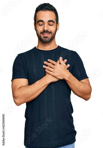 Young hispanic man wearing casual clothes smiling with hands on chest with closed eyes and grateful gesture on face. health concept.
