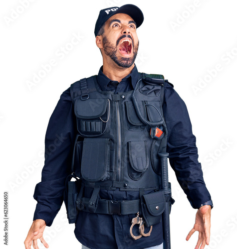 Young hispanic man wearing police uniform angry and mad screaming frustrated and furious, shouting with anger. rage and aggressive concept.