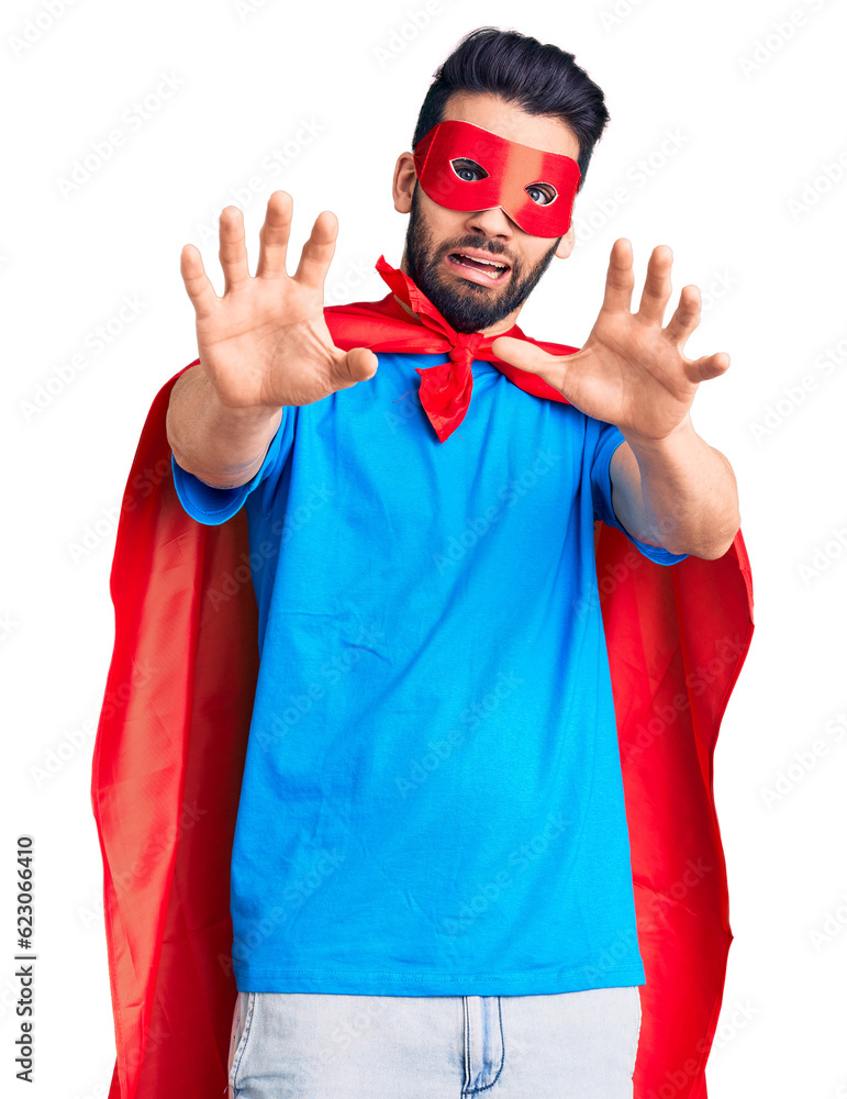 Young handsome man with beard wearing super hero costume afraid and terrified with fear expression stop gesture with hands, shouting in shock. panic concept. Young handsome man with beard wearing super hero costume afraid and terrified with fear expression stop gesture with hands, shouting in shock. panic concept.