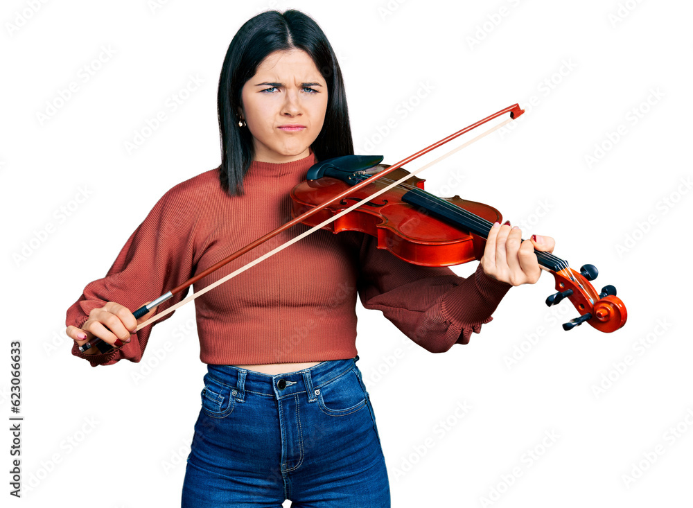 Young brunette woman with blue eyes playing violin skeptic and nervous, frowning upset because of problem. negative person. Young brunette woman with blue eyes playing violin skeptic and nervous, frowning upset because of problem. negative person.