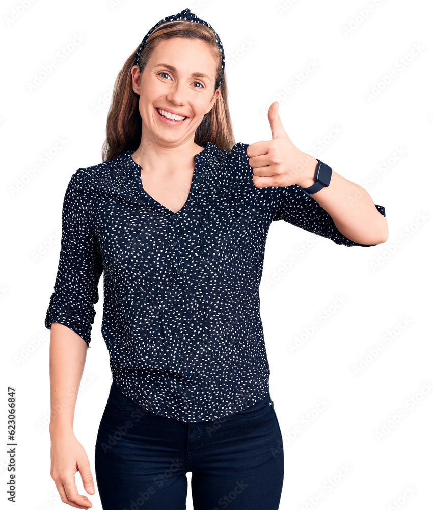 Young beautiful blonde woman wearing casual shirt smiling happy and positive, thumb up doing excellent and approval sign Young beautiful blonde woman wearing casual shirt smiling happy and positive, thumb up doing excellent and approval sign