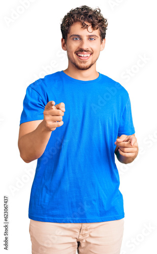 Young handsome man with curly hair wearing casual clothes pointing fingers to camera with happy and funny face. good energy and vibes. © Krakenimages.com