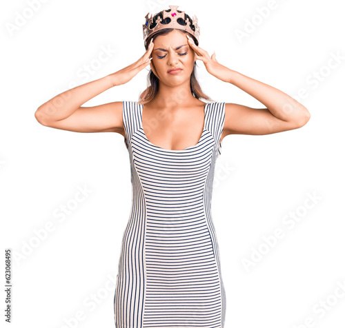 Young beautiful woman wearing king crown suffering from headache desperate and stressed because pain and migraine. hands on head.