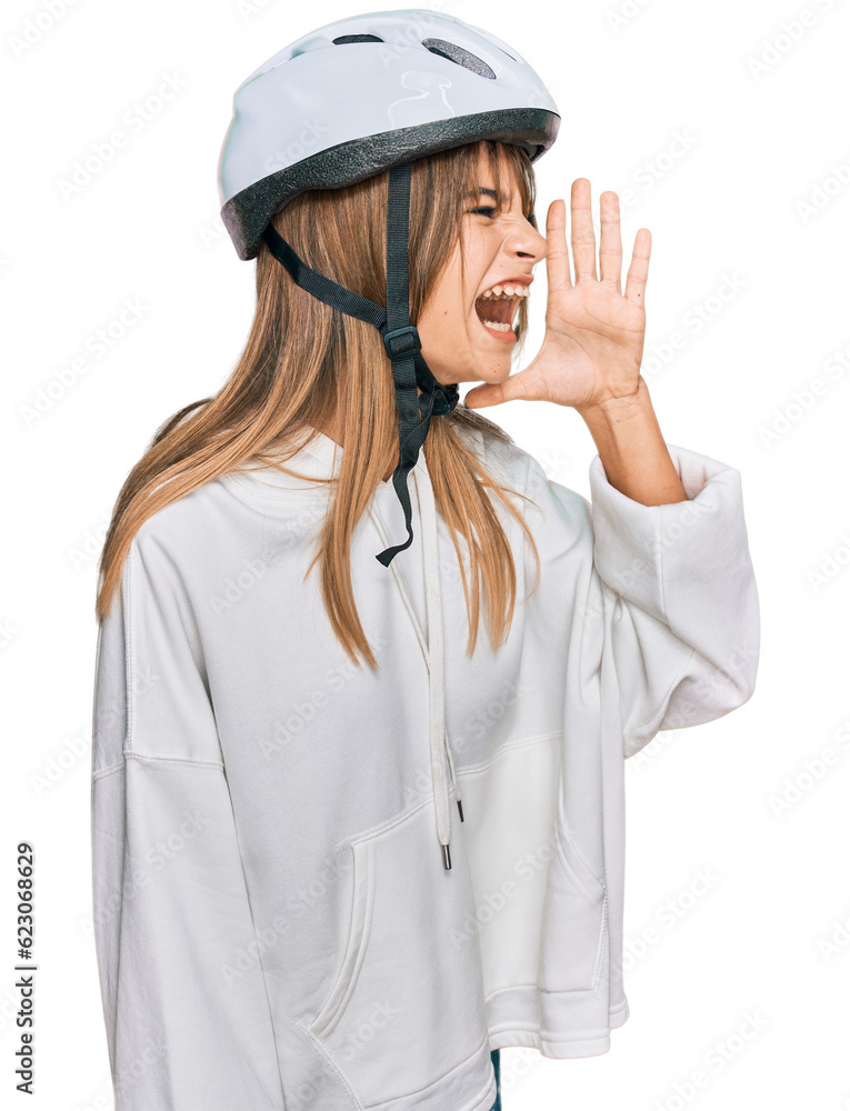 Teenager caucasian girl wearing bike helmet shouting and screaming loud to side with hand on mouth. communication concept. Teenager caucasian girl wearing bike helmet shouting and screaming loud to side with hand on mouth. communication concept.