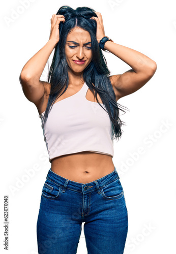 Beautiful hispanic woman wearing casual clothes suffering from headache desperate and stressed because pain and migraine. hands on head.
