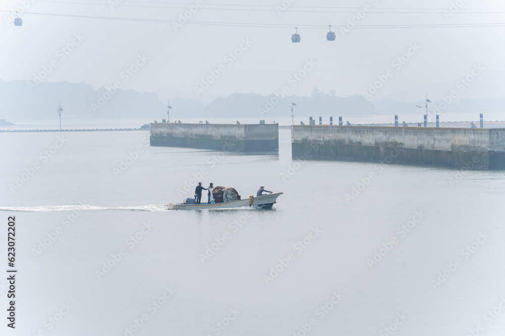 A fishing boat returning to the port on a foggy rainy day