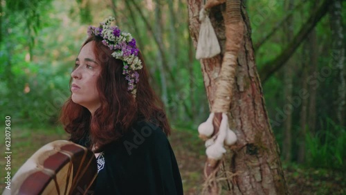 druid girl in a forest playing a shamanic drum medium close shot photo