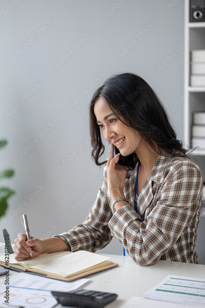 Beautiful asian woman talking on the phone, businesswoman working in office attentively to grow and modernize start-up business, she is analyzing company's market and financial data. Beautiful asian woman talking on the phone, businesswoman working in office attentively to grow and modernize start-up business, she is analyzing company's market and financial data.
