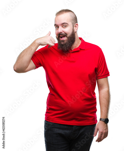 Young caucasian hipster man wearing red shirt over isolated background smiling doing phone gesture with hand and fingers like talking on the telephone. Communicating concepts.