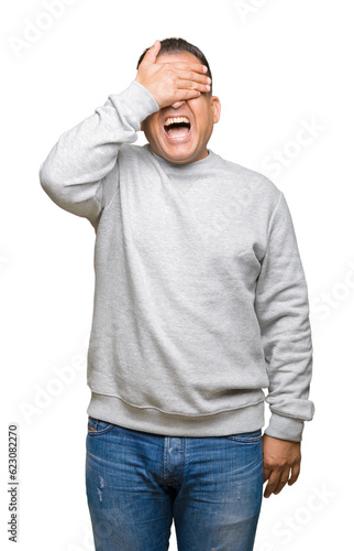 Middle age arab man wearing sport sweatshirt over isolated background smiling and laughing with hand on face covering eyes for surprise. Blind concept. © Krakenimages.com