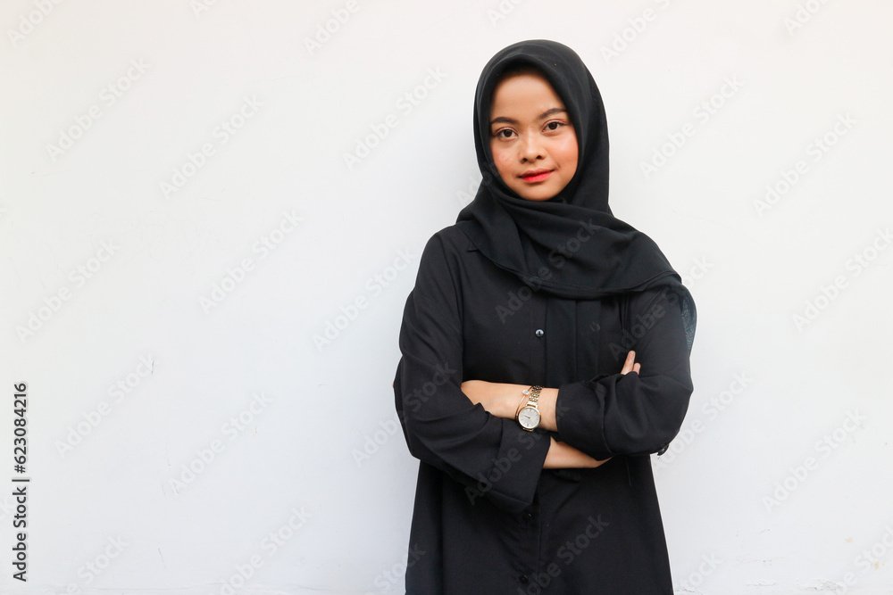 Beautiful smiling Asian woman in a black shirt and hijab crossed arms chest and looking confident isolated over white background Beautiful smiling Asian woman in a black shirt and hijab crossed arms chest and looking confident isolated over white background