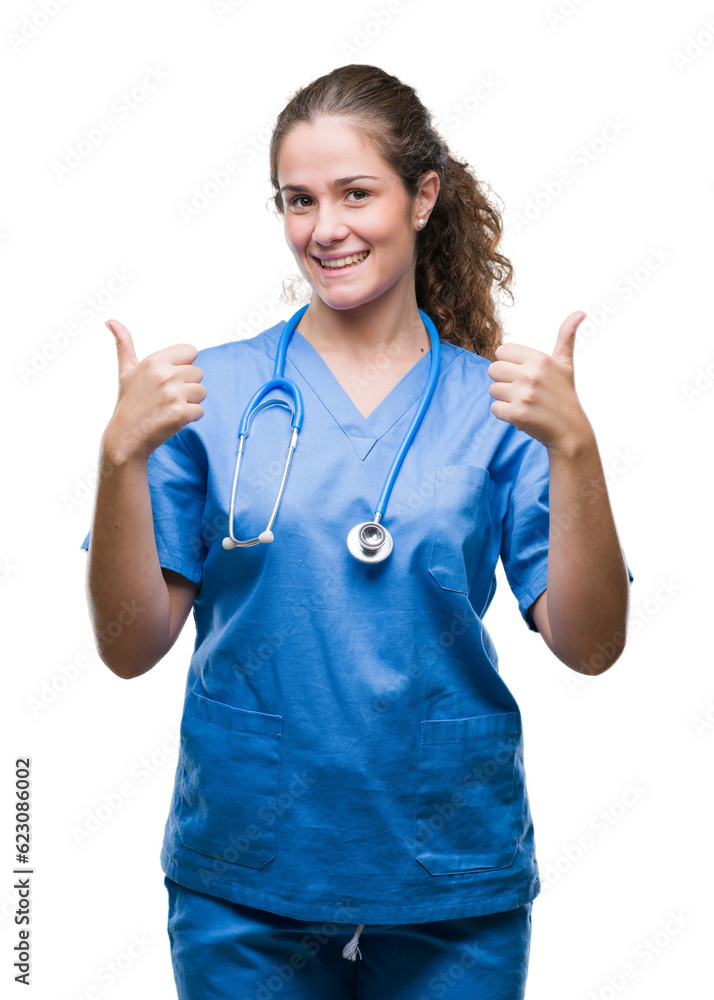 Young brunette doctor girl wearing nurse or surgeon uniform over isolated background success sign doing positive gesture with hand, thumbs up smiling and happy. Looking at the camera Young brunette doctor girl wearing nurse or surgeon uniform over isolated background success sign doing positive gesture with hand, thumbs up smiling and happy. Looking at the camera
