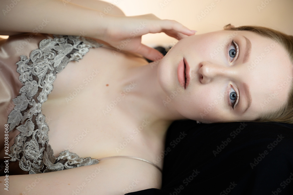 Calm young woman with blue eyes on pillow.