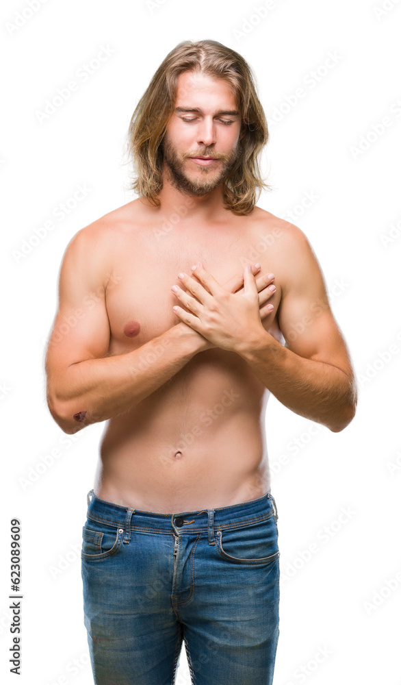 Obraz premium Young handsome shirtless man with long hair showing sexy body over isolated background smiling with hands on chest with closed eyes and grateful gesture on face. Health concept.