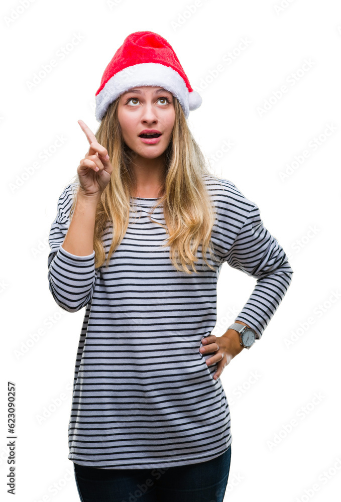 Young beautiful blonde woman wearing christmas hat over isolated background pointing finger up with successful idea. Exited and happy. Number one. Young beautiful blonde woman wearing christmas hat over isolated background pointing finger up with successful idea. Exited and happy. Number one.