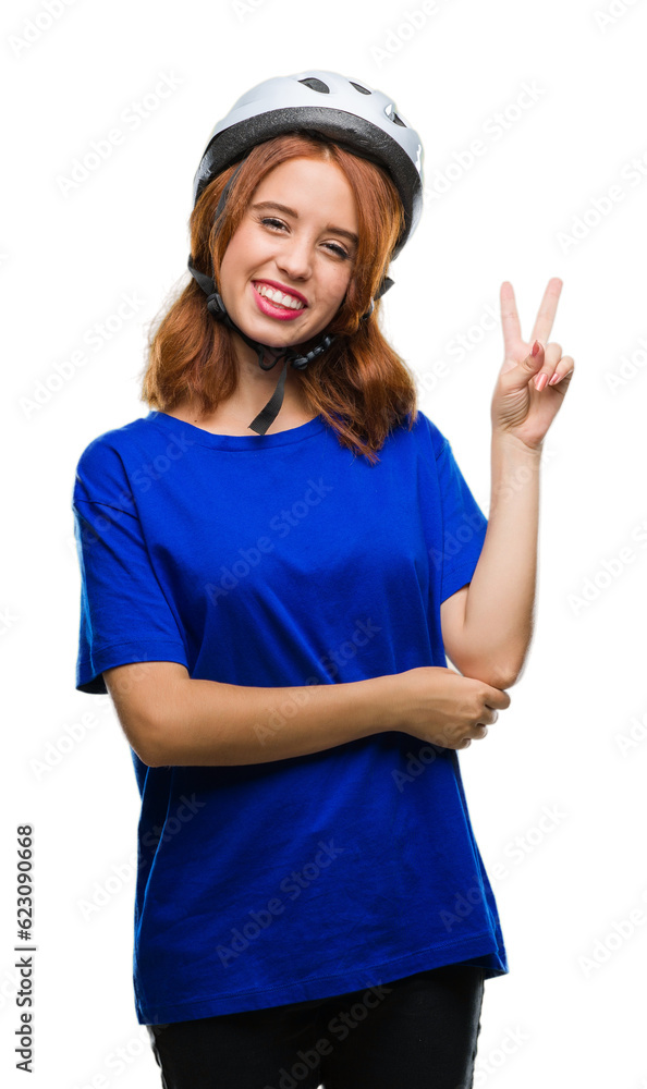 Young beautiful woman wearing cyclist helmet over isolated background smiling with happy face winking at the camera doing victory sign. Number two. Young beautiful woman wearing cyclist helmet over isolated background smiling with happy face winking at the camera doing victory sign. Number two.
