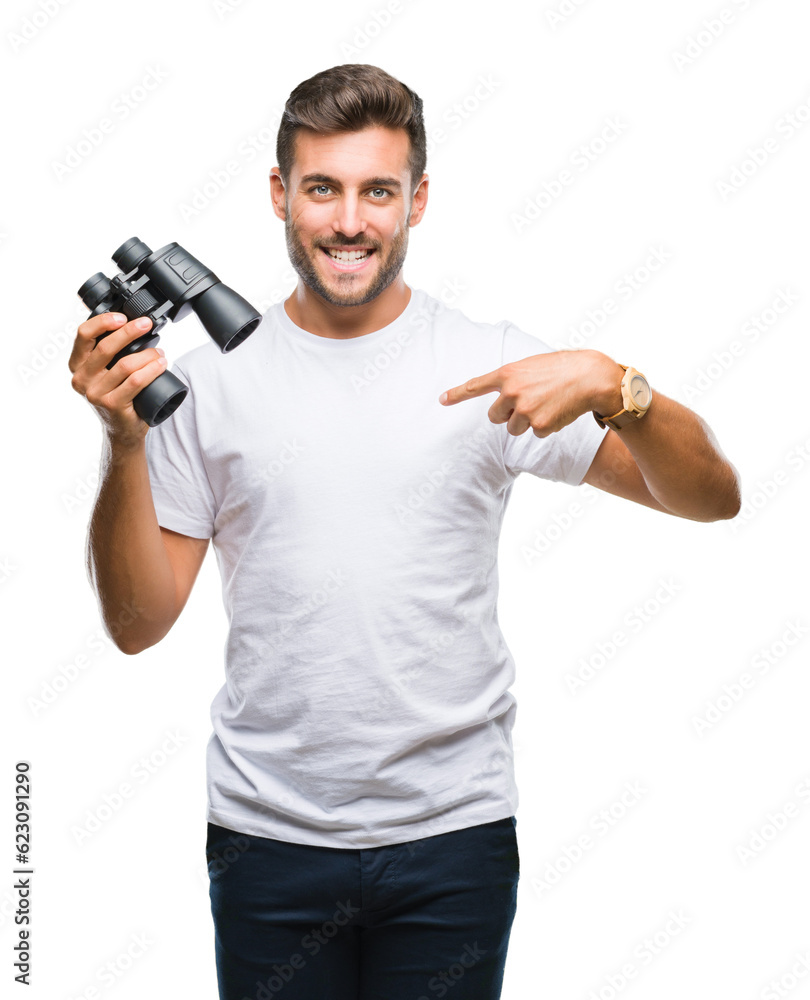 Young handsome man looking through binoculars over isolated background with surprise face pointing finger to himself Young handsome man looking through binoculars over isolated background with surprise face pointing finger to himself