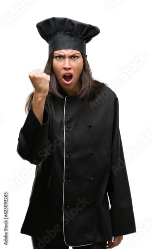 Young hispanic cook woman wearing chef uniform annoyed and frustrated shouting with anger, crazy and yelling with raised hand, anger concept