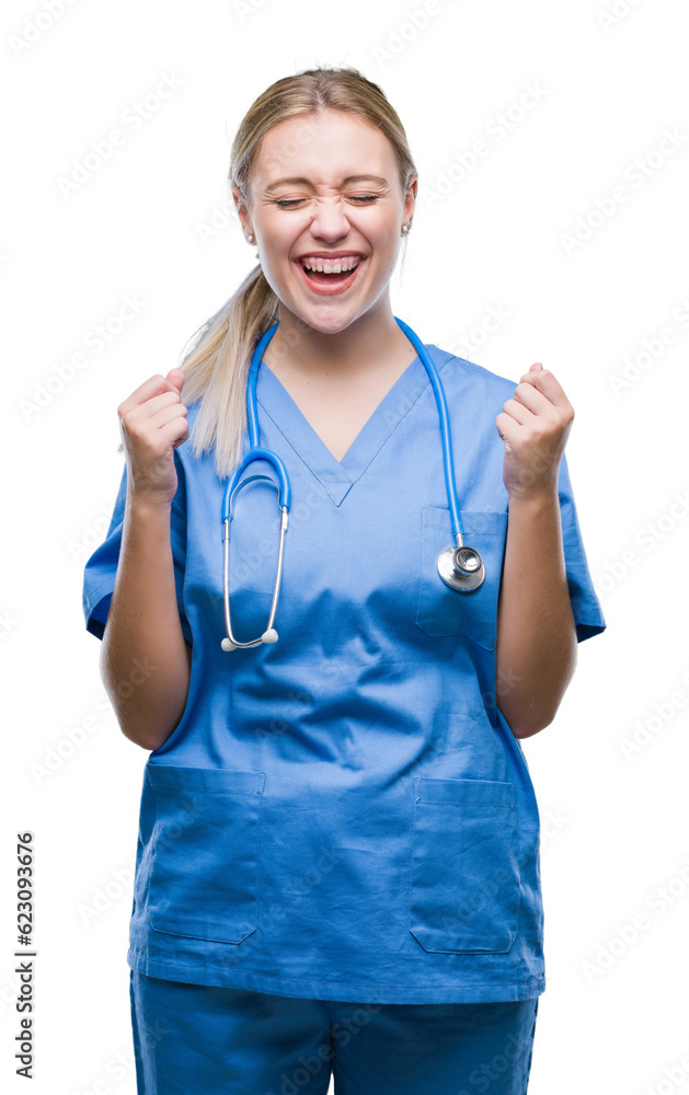 Young blonde surgeon doctor woman over isolated background excited for success with arms raised celebrating victory smiling. Winner concept. Young blonde surgeon doctor woman over isolated background excited for success with arms raised celebrating victory smiling. Winner concept.
