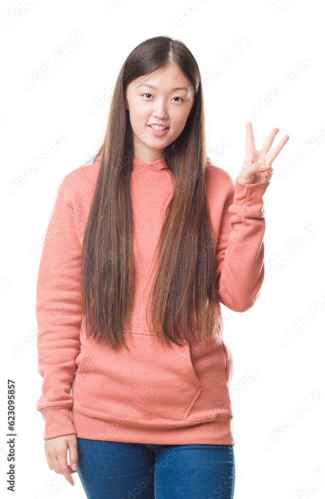 Young Chinese woman over isolated background wearing sport sweathshirt showing and pointing up with fingers number three while smiling confident and happy. Young Chinese woman over isolated background wearing sport sweathshirt showing and pointing up with fingers number three while smiling confident and happy.