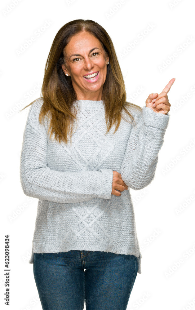 Beautiful middle age adult woman wearing winter sweater over isolated background with a big smile on face, pointing with hand and finger to the side looking at the camera. Beautiful middle age adult woman wearing winter sweater over isolated background with a big smile on face, pointing with hand and finger to the side looking at the camera.