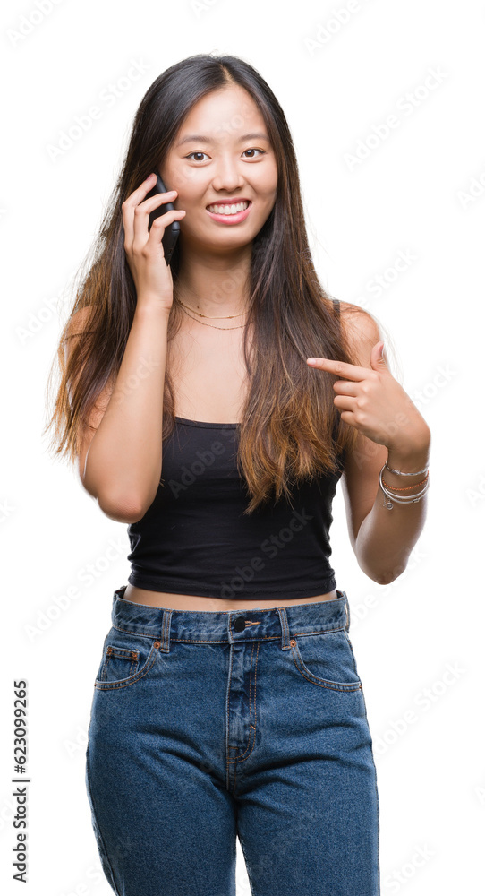 Young asian woman speaking on the phone over isolated background with surprise face pointing finger to himself Young asian woman speaking on the phone over isolated background with surprise face pointing finger to himself