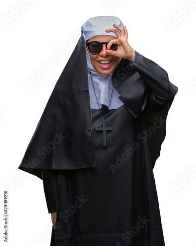 Middle age senior catholic nun woman wearing sunglasses over isolated background doing ok gesture with hand smiling, eye looking through fingers with happy face.