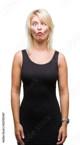 Young beautiful blonde attractive woman wearing elegant dress over isolated background making fish face with lips, crazy and comical gesture. Funny expression. © Krakenimages.com