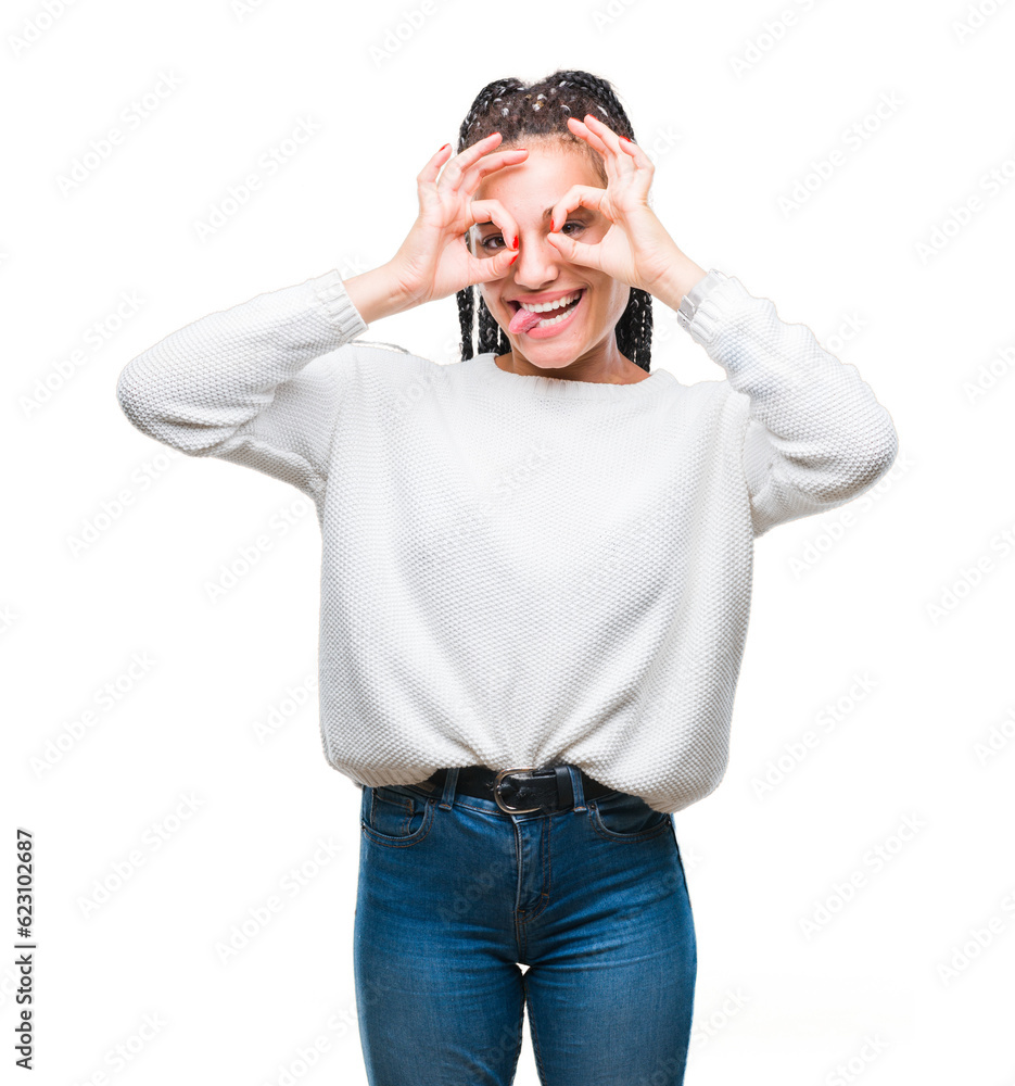 Young braided hair african american girl wearing winter sweater over isolated background doing ok gesture like binoculars sticking tongue out, eyes looking through fingers. Crazy expression.