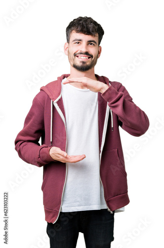 Young handsome man over isolated background gesturing with hands showing big and large size sign, measure symbol. Smiling looking at the camera. Measuring concept.