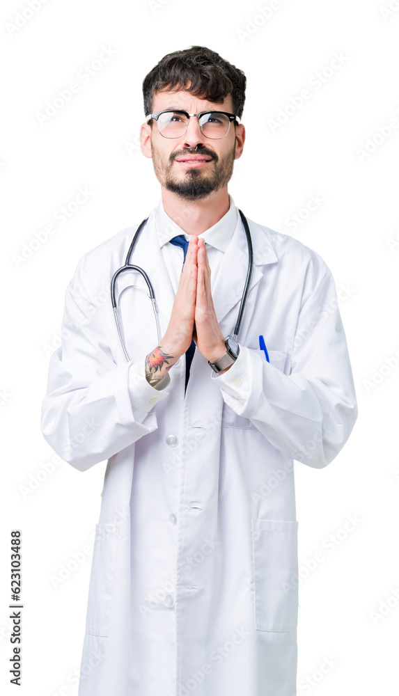 Young doctor man wearing hospital coat over isolated background begging and praying with hands together with hope expression on face very emotional and worried. Asking for forgiveness Young doctor man wearing hospital coat over isolated background begging and praying with hands together with hope expression on face very emotional and worried. Asking for forgiveness
