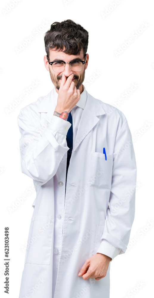 Young professional scientist man wearing white coat over isolated background smelling something stinky and disgusting, intolerable smell, holding breath with fingers on nose. Bad smells concept. Young professional scientist man wearing white coat over isolated background smelling something stinky and disgusting, intolerable smell, holding breath with fingers on nose. Bad smells concept.