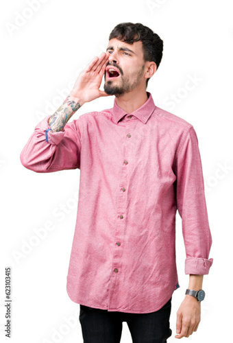 Young handsome man wearing pink shirt over isolated background shouting and screaming loud to side with hand on mouth. Communication concept.