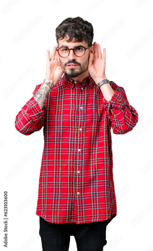 Young handsome man wearing glasses over isolated background Trying to hear both hands on ear gesture, curious for gossip. Hearing problem, deaf Young handsome man wearing glasses over isolated background Trying to hear both hands on ear gesture, curious for gossip. Hearing problem, deaf