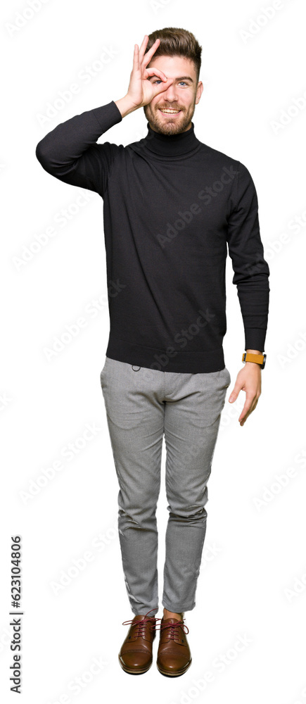 Young handsome blond man wearing winter sweater doing ok gesture with hand smiling, eye looking through fingers with happy face. Young handsome blond man wearing winter sweater doing ok gesture with hand smiling, eye looking through fingers with happy face.