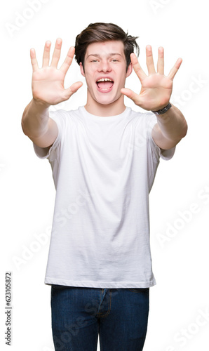 Young handsome man wearing casual white t-shirt over isolated background showing and pointing up with fingers number ten while smiling confident and happy.