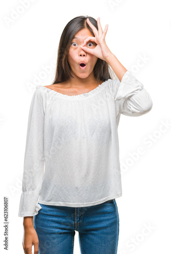 Young asian woman over isolated background doing ok gesture shocked with surprised face, eye looking through fingers. Unbelieving expression. © Krakenimages.com