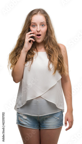 Young blonde woman using smartphone scared in shock with a surprise face, afraid and excited with fear expression