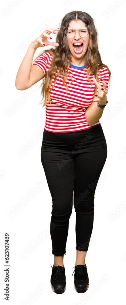 Fototapeta premium Young beautiful woman wearing glasses Shouting frustrated with rage, hands trying to strangle, yelling mad