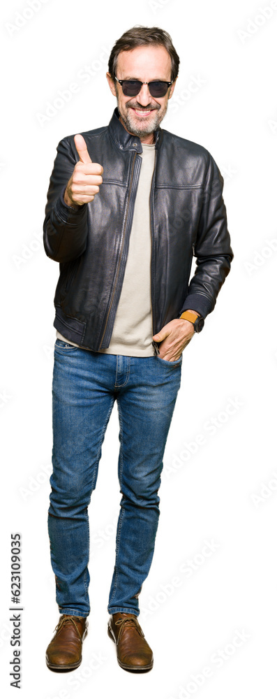 Middle age handsome man wearing sunglasses and black leather jacket doing happy thumbs up gesture with hand. Approving expression looking at the camera with showing success. Middle age handsome man wearing sunglasses and black leather jacket doing happy thumbs up gesture with hand. Approving expression looking at the camera with showing success.