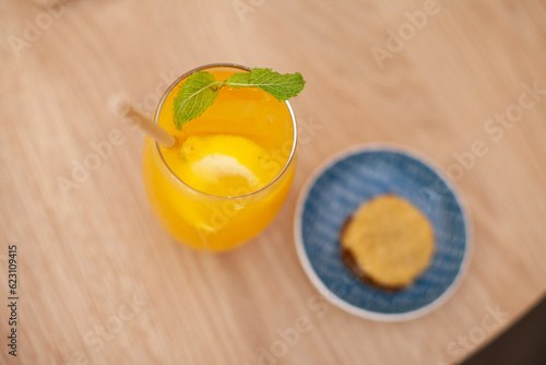 Orange cocktail drink with a cookie at table at cafe