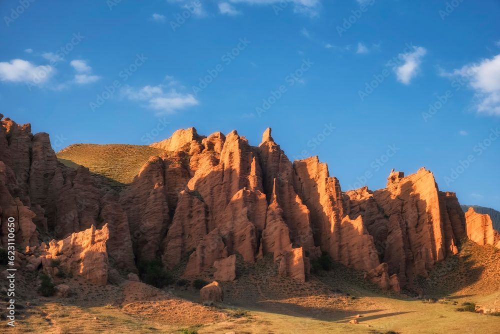 Tract Zhaman uy in the mountains of Kazakhstan. Fantastic clay remains of red color against blue sky.