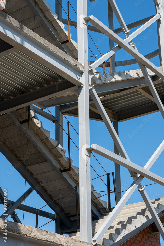 Construction of a building using scaffolding. Facade restoration work. Fragment of scaffolding and stairs against house wall. Safety at the construction site Construction of a building using scaffolding. Facade restoration work. Fragment of scaffolding and stairs against house wall. Safety at the construction site
