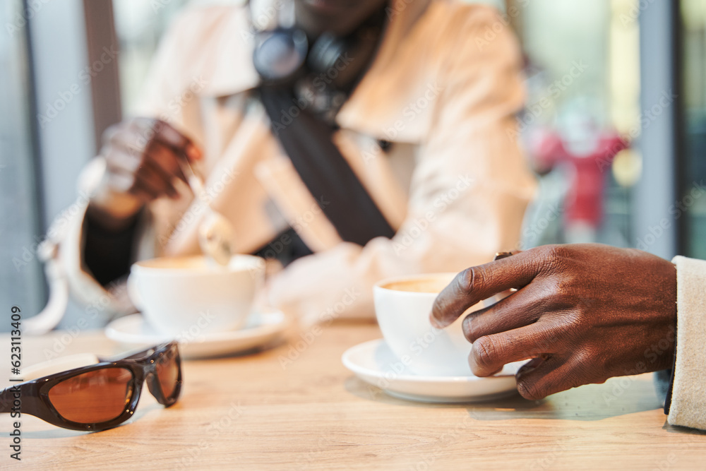 Cropped view of the two multiracial brothers enjoying hot beverage on meeting in cafe Cropped view of the two multiracial brothers enjoying hot beverage on meeting in cafe