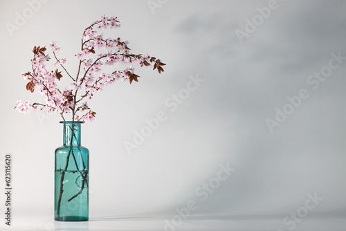 cherry blossom ikebana in a blue vase on a left side